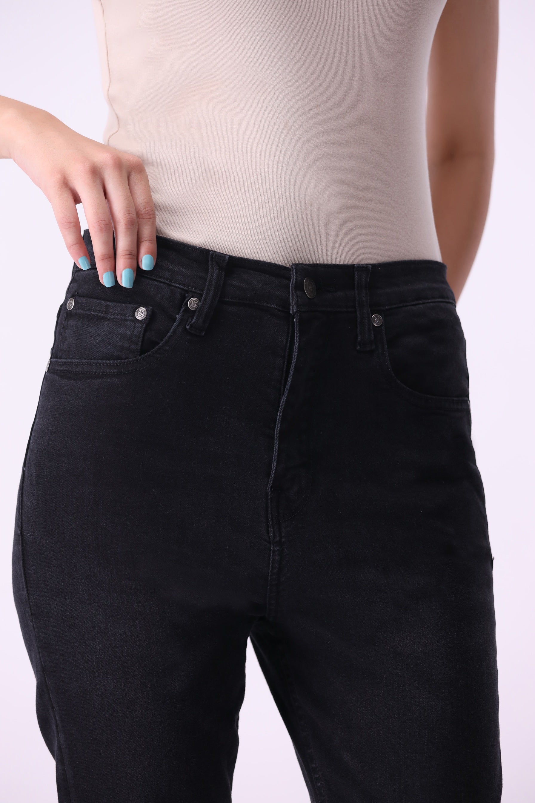 Close-up front view of women’s Beryoza jeans in black wash, paired with a beige tank top.