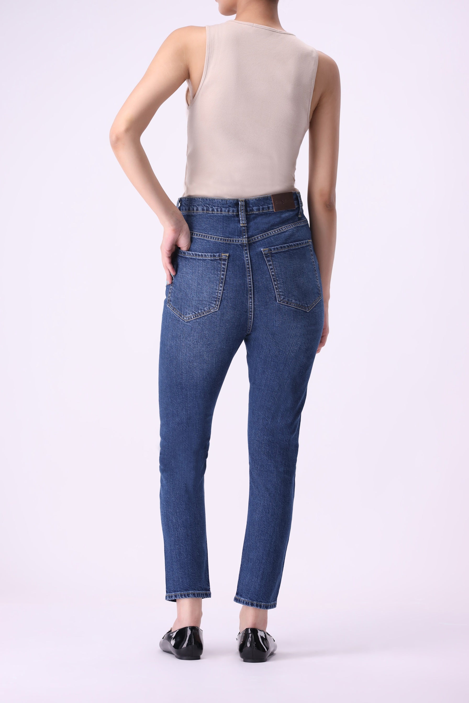 Back view of women’s dark indigo skinny jeans, high-rise ankle-length with stretch