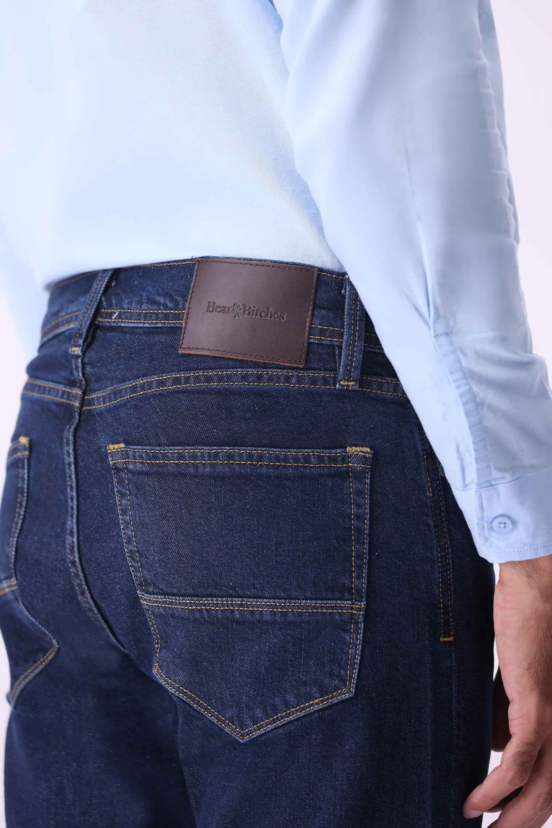 Back view of Kuma men's jeans featuring classic pocket styling and a genuine leather brand patch.