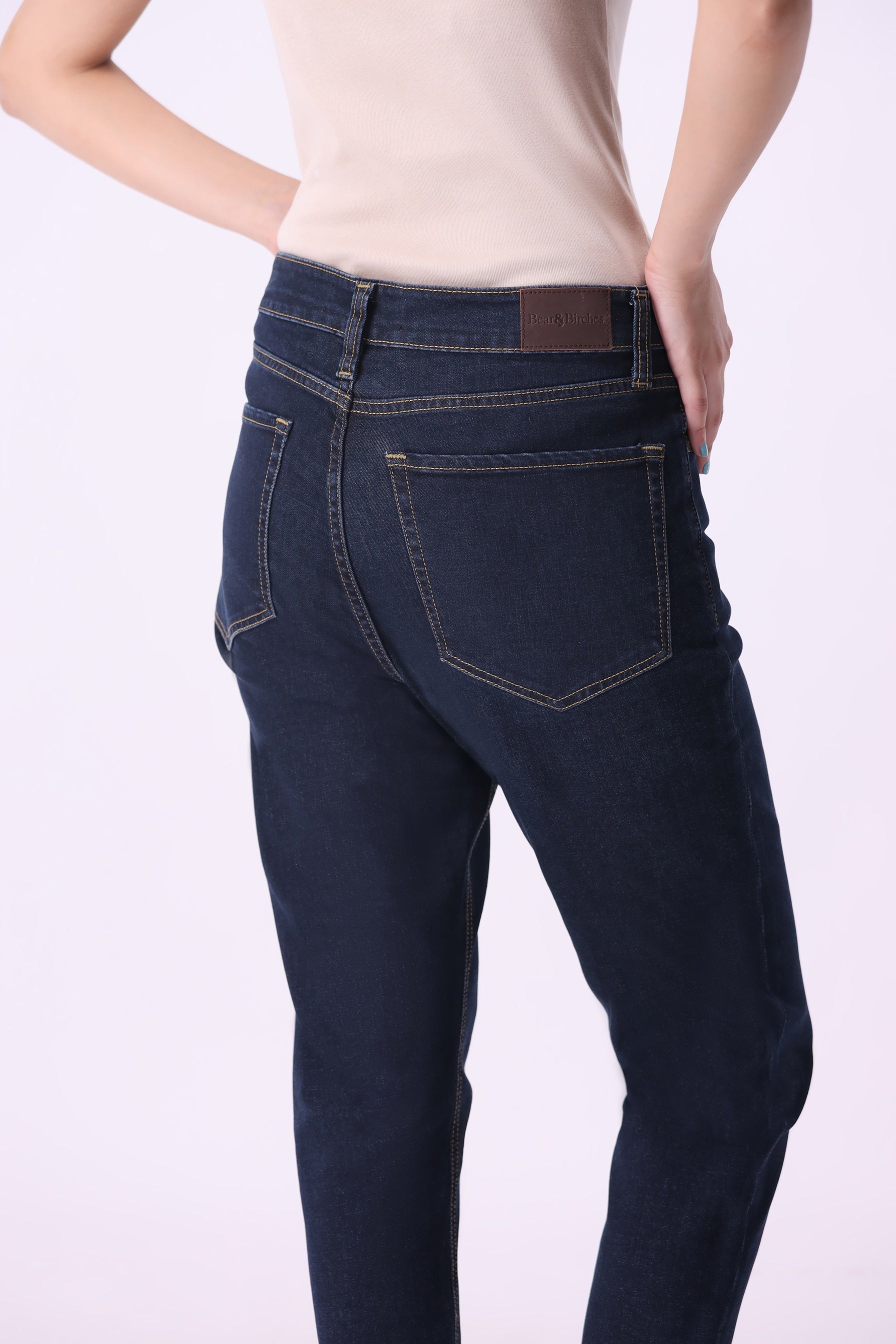 Angled back view of Bear & Birches Birke women’s tapered high-rise ankle jeans, dark wash