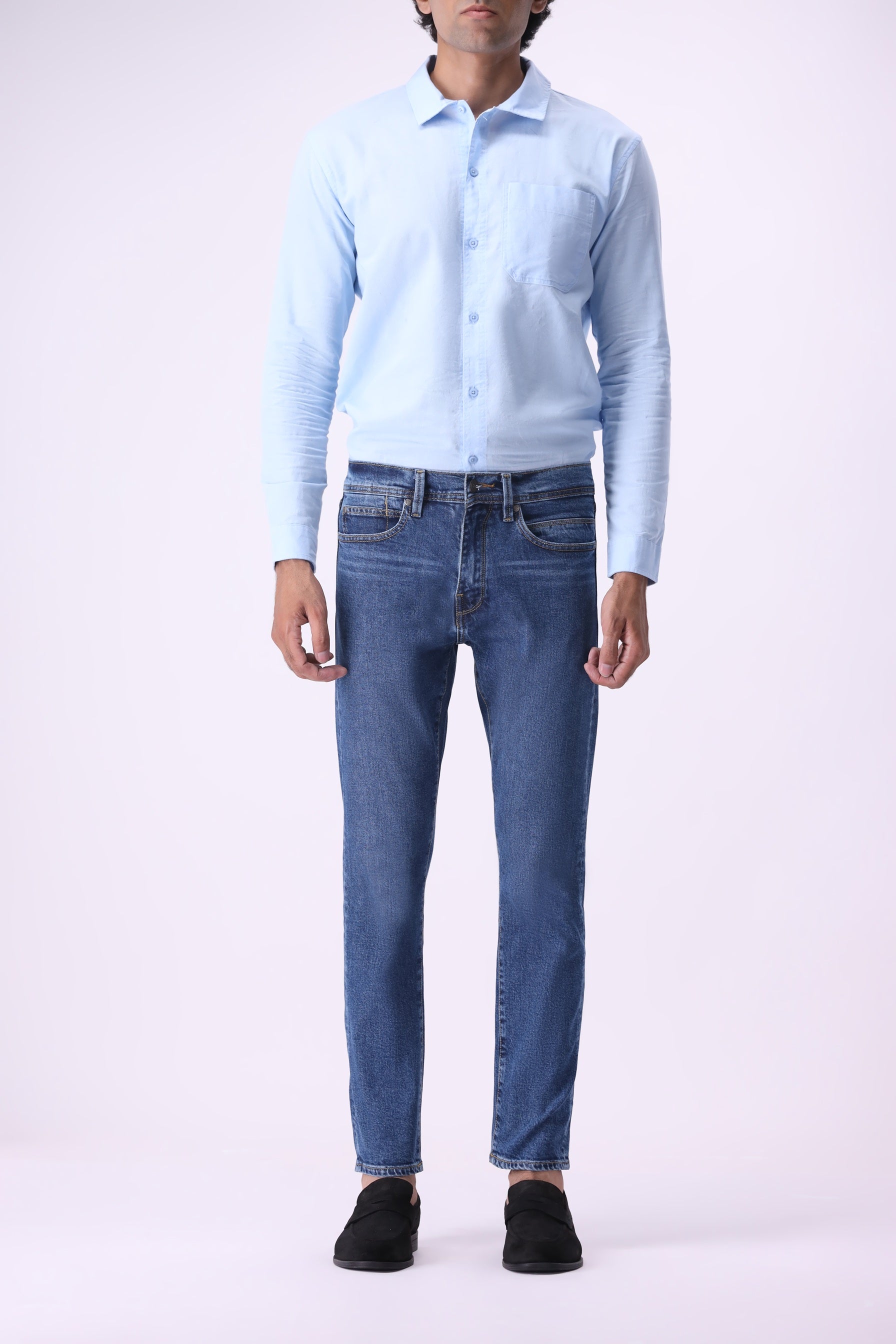 Full front view of men’s Baloo slim fit dark blue jeans styled with a light blue button-up shirt