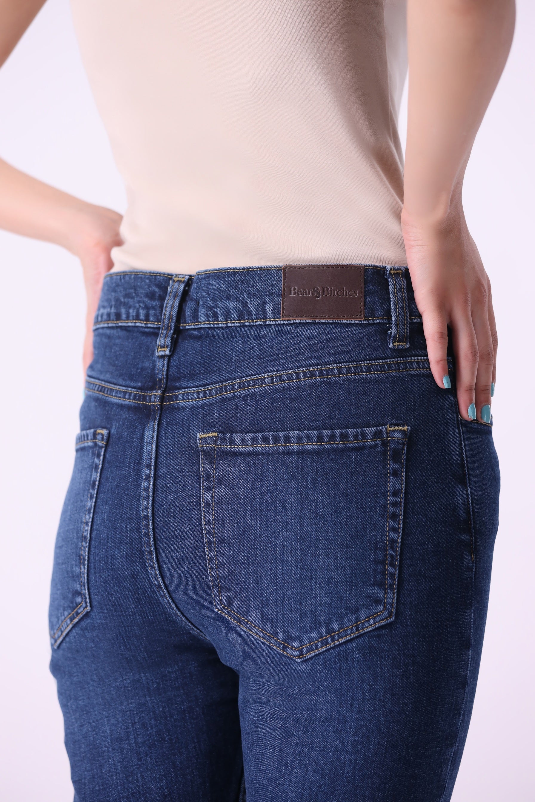 Back view close-up of women’s Beryoza jeans in medium dark indigo wash with visible leather patch.
